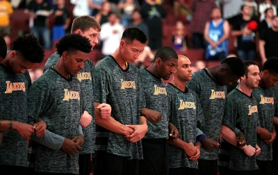 Los Angeles Lakers players standing arm-in-arm during the National Anthem at a preseason game