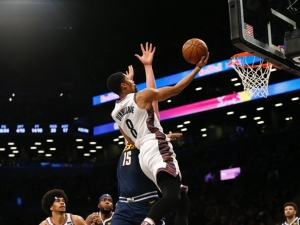Brooklyn Nets guard, Spencer Dinwiddie, goes for a layup with Denver&#039;s Nikola Jokic defending at the Barclays Center on December 8, 2019. Brooklyn Nets defeat the Denver Nuggets 105-102.