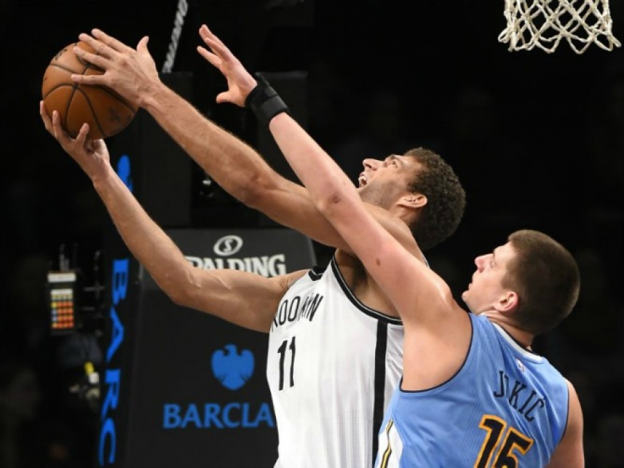 Brook Lopez leaps to the basket over Denver Nuggets forward Nikola Jokic (15) in the first half of an NBA basketball game at Barclays Center 